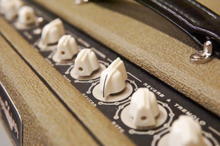 Close-up of a guitar amplifier control panel with knobs and labels.