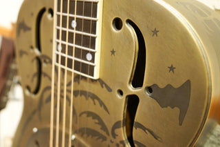Close-up of a gold guitar with palm tree design