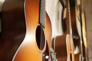 Close-up of a brown acoustic guitar with other guitars in the background