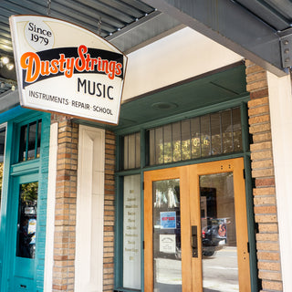 Storefront and sign for Dusty Strings music store in Seattle listing guitars, mandolins, banjos, and more, plus a music school