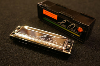 Lee Oskar harmonica with packaging on a dark surface