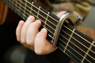 Close-up of a guitar capo being used on a guitar neck.