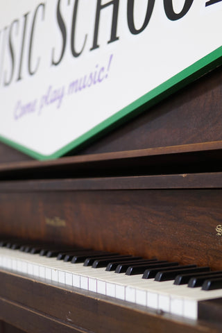 Close-up of a piano with a sign in the background advertising music lessons.