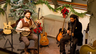 Performers playing banjo and guitar on a stage decorated for Christmas