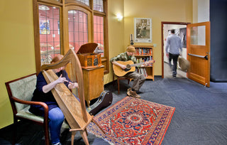 Music school lobby with someone playing harp and someone playing guitar