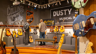 Two people standing on a low stage looking at resonator guitars