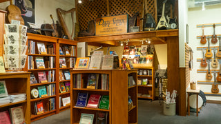 Old Dusty Strings handcrafted hammered dulcimers wooden sign above shelves full of music books